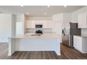 Open kitchen features stainless steel appliances, white cabinets, a center island, and hardwood floors at 15286 Fillmore St, Thornton, CO 80602