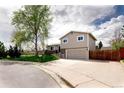 Inviting home exterior with a large driveway, tidy lawn, and mature trees at 6141 S Estes St, Littleton, CO 80123