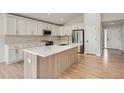 Modern kitchen boasts stainless steel appliances, custom cabinets, an island, and hardwood floors at 15870 Duckweed Ct, Parker, CO 80134