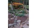 Landscaped backyard with a wood pergola, patio set, lighting, and trees at 8171 S Homesteader Dr, Morrison, CO 80465