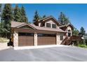 A beautiful shot of the home's exterior featuring stone accents, a porch, and a three-car garage at 8171 S Homesteader Dr, Morrison, CO 80465