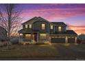 Two-story house with stone accents, a three-car garage, and a covered porch at dusk at 7112 E 131St Pl, Thornton, CO 80602