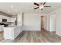 Open-concept living area with modern light fixtures and wood-look flooring, seamlessly flowing into the kitchen at 48215 Shetland Dr, Bennett, CO 80102