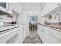 Galley kitchen with white cabinetry, stainless appliances, and an adjacent dining area at 7375 E Quincy Ave # 204, Denver, CO 80237