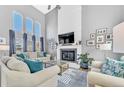 Bright living room with a cozy fireplace, a large TV, soaring ceilings, and oversized windows at 15592 E Kenyon Ave, Aurora, CO 80013