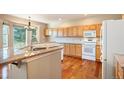 Well-lit kitchen with granite countertops, white appliances, a bay window and wood flooring at 15577 Greenstone Cir, Parker, CO 80134