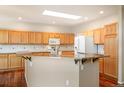 Bright kitchen with island, granite countertops, stainless appliances and light wood cabinetry at 15577 Greenstone Cir, Parker, CO 80134