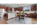 A kitchen with stainless steel appliances, wood cabinets, a large kitchen island, and an attached dining table at 5984 S Paris Pl, Greenwood Village, CO 80111