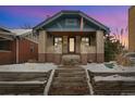 Charming craftsman bungalow with brick facade, covered porch, and snowy landscaping at 525 N Pearl St, Denver, CO 80203