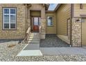 Inviting front entrance with stone accents, a partial glass front door, and landscaped front yard at 34 Leafy Aster Ln, Castle Rock, CO 80104