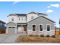 Beautiful two-story home featuring gray siding, stone accents, a red front door, and a well-maintained lawn at 3131 Keepsake Way, Castle Rock, CO 80109