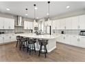 Bright kitchen features a large island, white cabinets, modern pendant lighting, and backsplash at 3131 Keepsake Way, Castle Rock, CO 80109