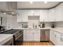 Modern kitchen featuring white cabinets, stainless steel appliances, quartz countertops, and hardwood floors at 12292 W 65Th Ave, Arvada, CO 80004