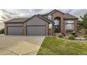 Beautiful brick and gray two-story home with a three-car garage and well-manicured lawn at 12693 W 82Nd Ln, Arvada, CO 80005