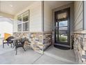 Cozy front porch seating area with stone accents and a stylish front door with glass, creating a welcoming entrance at 14670 Guernsey Dr, Mead, CO 80542
