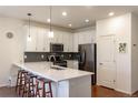 Well-lit kitchen featuring a large island with seating, stainless steel appliances, and stylish backsplash at 8951 E 59Th Pl, Denver, CO 80238