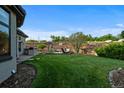 Expansive backyard with lush green grass, terraced landscaping, and outdoor seating area at 5810 Amber Ridge Dr, Castle Pines, CO 80108