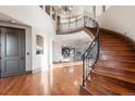 Grand foyer with curved staircase, hardwood floors, and views of the living room with a stone fireplace at 5810 Amber Ridge Dr, Castle Pines, CO 80108