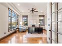 Well-lit home office with hardwood floors, tray ceilings, large windows, a ceiling fan, and classic furnishings at 5810 Amber Ridge Dr, Castle Pines, CO 80108