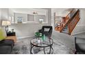 Open-concept living room features a cozy armchair, a stylish rug, and a staircase with wood railings in the background at 306 Monares Ln, Erie, CO 80516