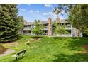 Building exterior with balconies and a grassy lawn with a path to the pond and seating area at 8335 Fairmount Dr # 9-201, Denver, CO 80247