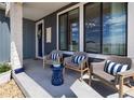 Cozy front porch featuring stylish wicker chairs with striped pillows and a small accent table at 6235 Stable View St, Castle Pines, CO 80108