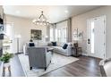 Spacious living room featuring a sectional sofa, modern chandelier, and large windows at 6235 Stable View St, Castle Pines, CO 80108