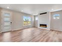 Bright living room featuring hardwood floors, fireplace, modern lighting, and large windows offering neighborhood views at 3314 N Haleyville Ct, Aurora, CO 80019