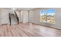 Spacious living room with hardwood floors, staircase, and large windows showcasing natural light and neighborhood views at 3314 N Haleyville Ct, Aurora, CO 80019