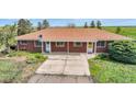 Low aerial view of a ranch-style home with a large driveway and covered front porch at 1614 N Manila Rd, Bennett, CO 80102
