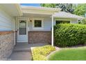 Cozy front porch with brick accents, a white door, and manicured landscaping at 7325 S Houstoun Waring Cir, Littleton, CO 80120