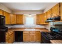 Functional kitchen with wooden cabinets, black appliances, and a window above the sink at 7325 S Houstoun Waring Cir, Littleton, CO 80120