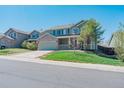 Charming two-story home with a well-manicured lawn and a two car garage on a bright sunny day at 5149 S Tibet St, Aurora, CO 80015