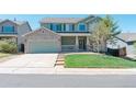 Charming two-story home with a well-manicured lawn and a two car garage on a bright sunny day at 5149 S Tibet St, Aurora, CO 80015