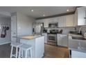 Modern kitchen with white cabinets, stainless steel appliances, island with bar seating and hardwood floors at 5431 E 129Th Ave, Thornton, CO 80241