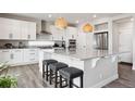 Bright kitchen features a large island, pendant lighting, stainless steel appliances, and sleek white cabinetry at 22025 E 45Th Ave, Aurora, CO 80019