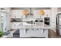 Bright kitchen boasts white cabinets, stainless steel appliances, and an expansive island with pendant lighting at 22025 E 45Th Ave, Aurora, CO 80019