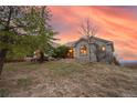 Exterior view of a single story home with arched windows surrounded by green grass and mature trees at 265 Ox Yoke Way, Monument, CO 80132