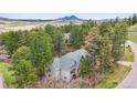 Aerial view of a wooded property with a gray home, surrounded by mature trees and mountain views at 4185 Cheyenne Dr, Larkspur, CO 80118