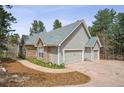 Beautiful home showcasing a three-car garage and stone accents in a tranquil, wooded setting at 4185 Cheyenne Dr, Larkspur, CO 80118