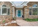 Stone home featuring a teal front door with large windows and meticulously landscaped entryway at 4185 Cheyenne Dr, Larkspur, CO 80118