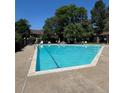 Large community pool with clear blue water surrounded by lounge chairs and lush trees at 1850 S Pitkin Cir # B, Aurora, CO 80017