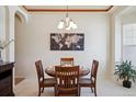 A dining room with a wooden table, four chairs, a chandelier, and a world map hanging on the wall at 8068 Dressage Rd, Littleton, CO 80125