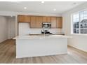 Modern kitchen features a central island, wood cabinets, stainless steel appliances and laminate floors at 1281 Rock Cliff Ave, Erie, CO 80516