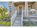 Inviting front porch with white railing and steps, complemented by vibrant landscaping and a modern door at 2419 Flats St, Erie, CO 80516