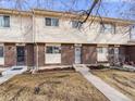 Charming townhome featuring a brick facade, tidy landscaping, and a concrete walkway leading to the front door at 1294 S Troy St, Aurora, CO 80012