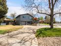 Exterior view showing a gray two-story home, large driveway, and mature trees at 6500 S Downing St, Centennial, CO 80121