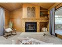 Living room with wood-paneled walls, vaulted ceiling, and brick fireplace with decorative accents at 9967 Lane St, Thornton, CO 80260