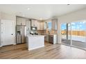 Bright kitchen featuring an island, stainless appliances, gray cabinetry, and sliding glass doors to a covered patio at 9484 Yampa St, Commerce City, CO 80022