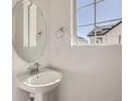 Half bathroom featuring a pedestal sink with round mirror and a window at 7213 Waterleaf Trl, Littleton, CO 80125